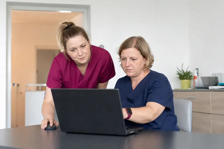 Pflegefachkraft und Pflegedienstleitung prüfen gemeinsam eine digitale Pflegedokumentation.